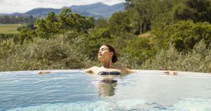 Woman in a low chlorine pool, relaxing, to show how to lower chlorine in pool water.