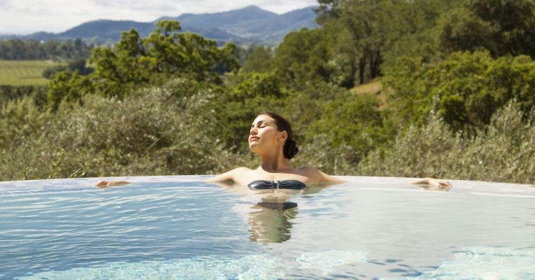 Woman in a low chlorine pool, relaxing, to show how to lower chlorine in pool water.